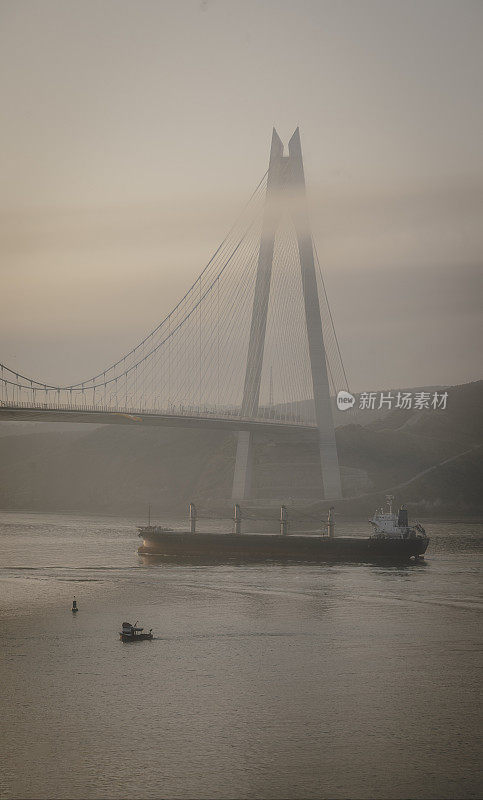 伊斯坦布尔雾蒙蒙的早晨:日出时分，货船从Yavuz Sultan Selim大桥下通过